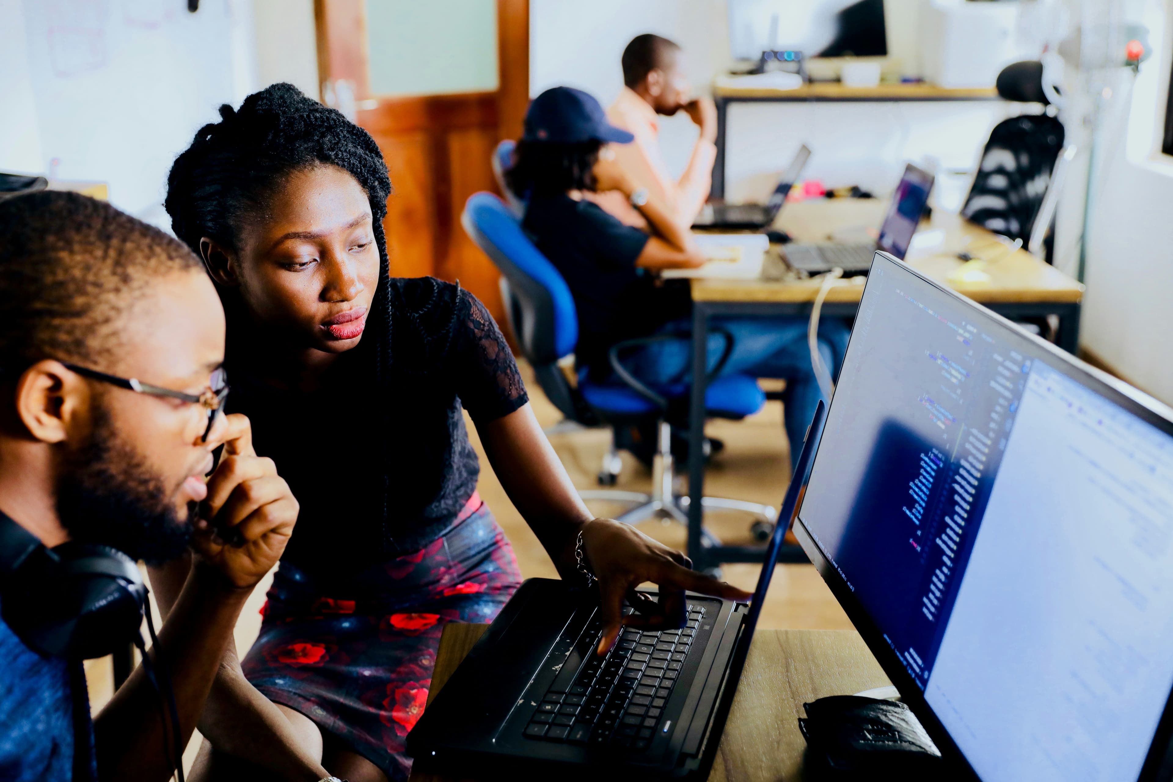 Duas pessoas discutem em frente à um computador.
